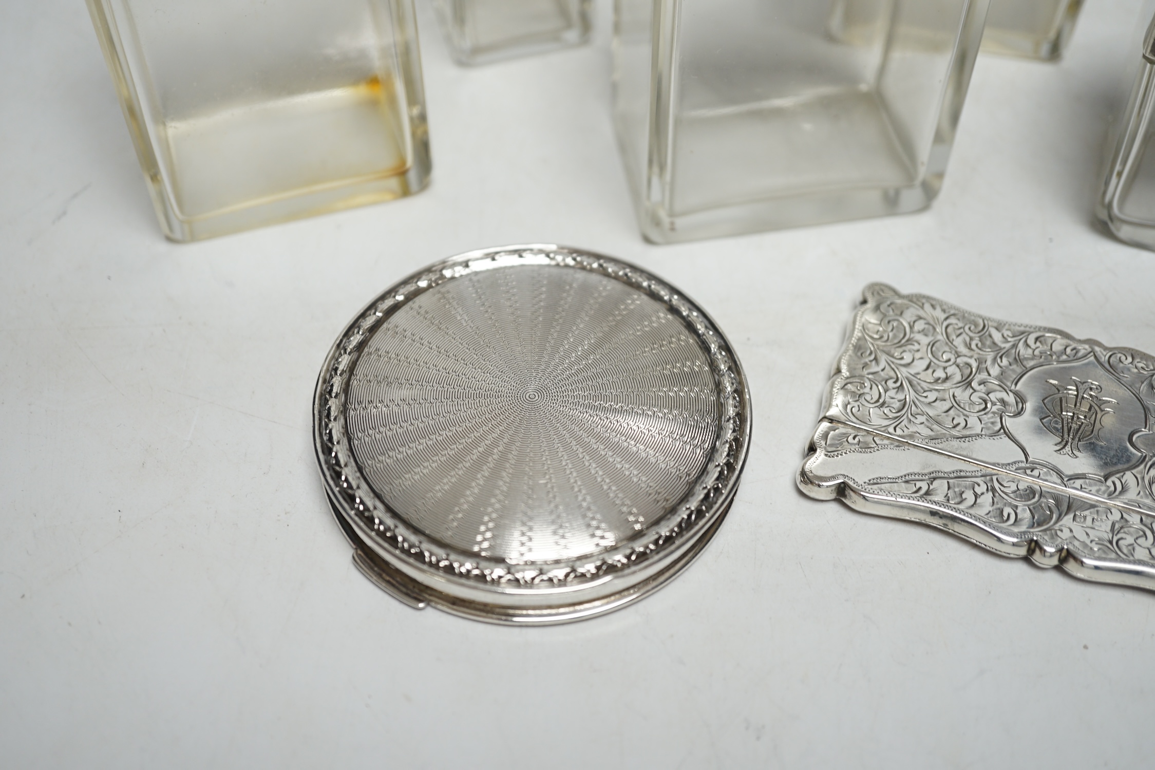 Five assorted silver topped glass toilet jars, a silver compact and an Edwardian engraved silver card case, Birmingham, 1902, 83mm.